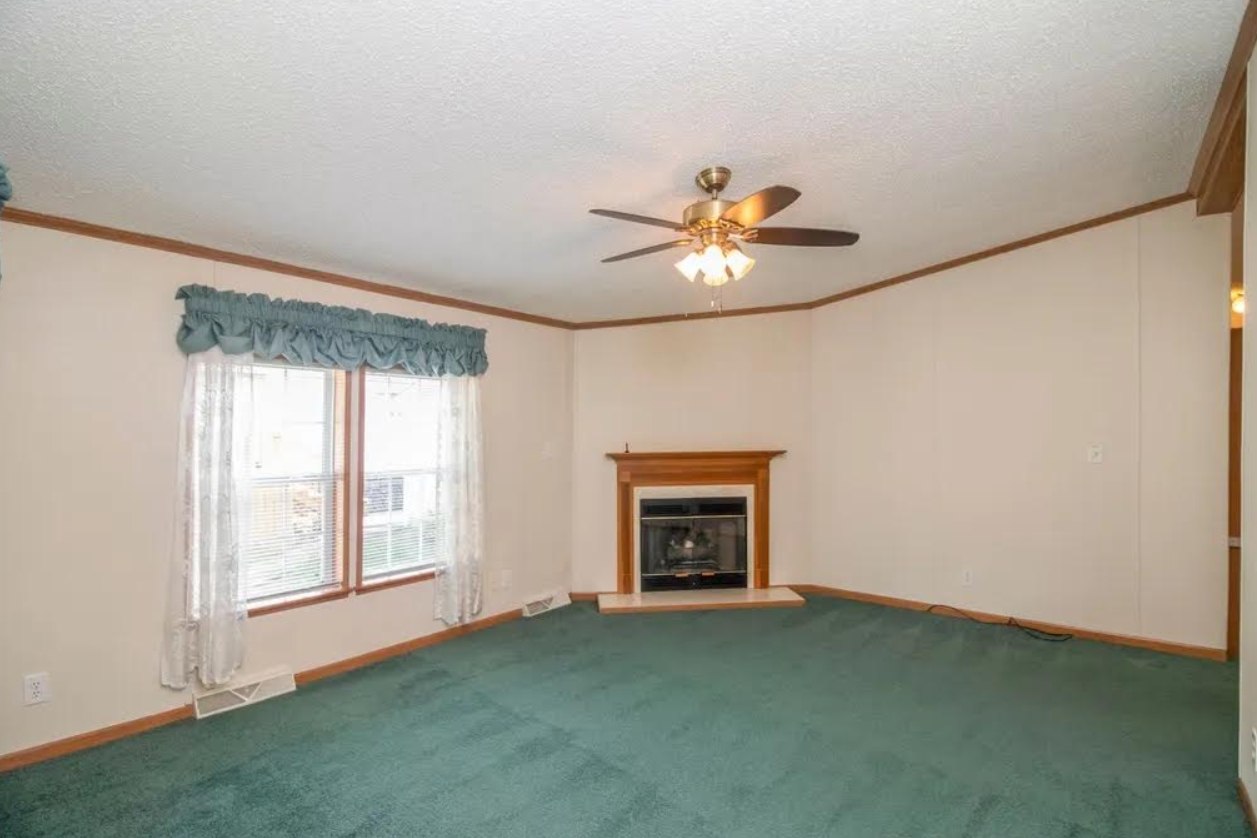 Fireplace room before — green carpet, oak mantle